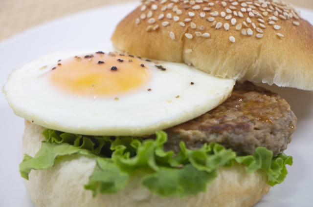 A delicious hamburger with a fried egg inside, viewed from a slightly elevated angle.This is an image of a tsukimi burger and does not represent any specific product or brand.