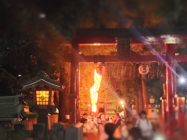 A shrine gate lit by lanterns on an autumn festival evening in Japan.