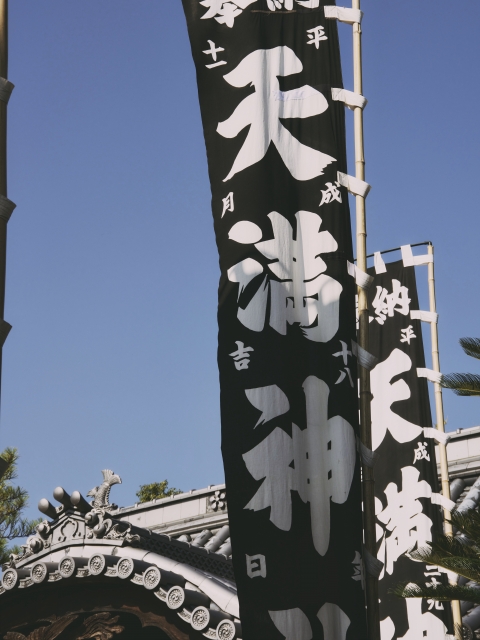 Festival banners fluttering in the autumn sky at a Tenmangu shrine.