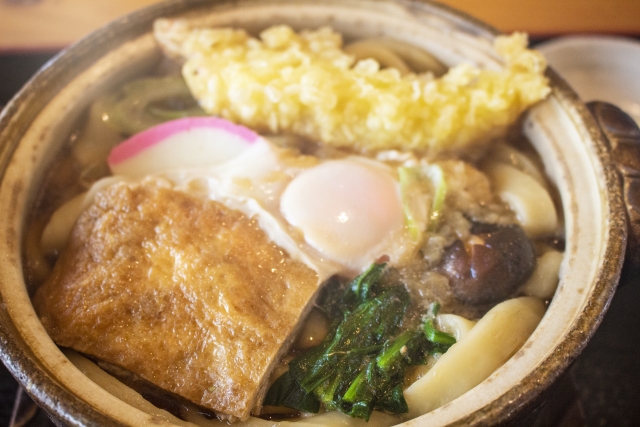 A steaming bowl of nabeyaki udon in a traditional clay pot